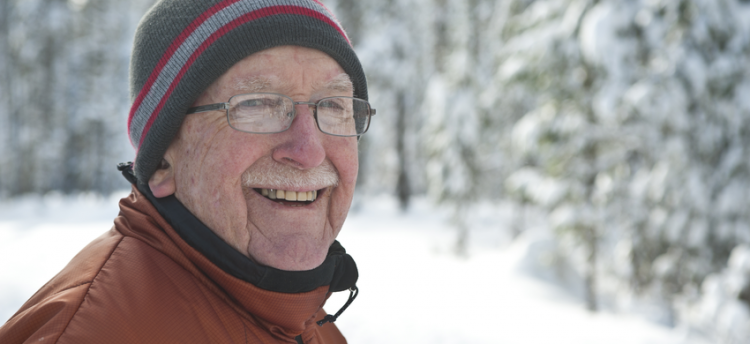An older person in the cold weather surrounded by snow.
